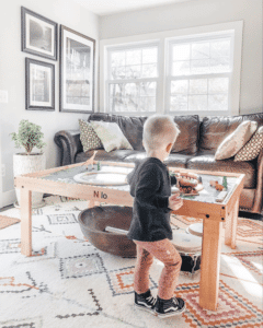 Toddler playing with toy train set on a Nilo childrens play table