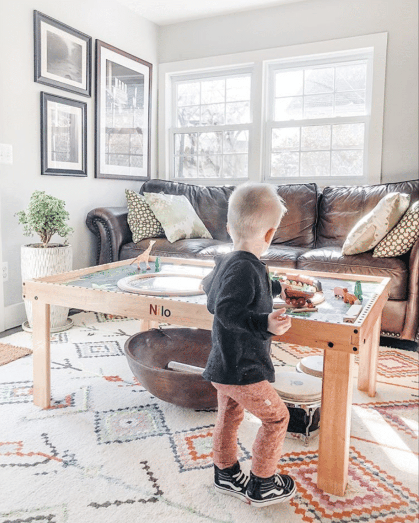 Toddler playing with toy train set on a Nilo childrens play table